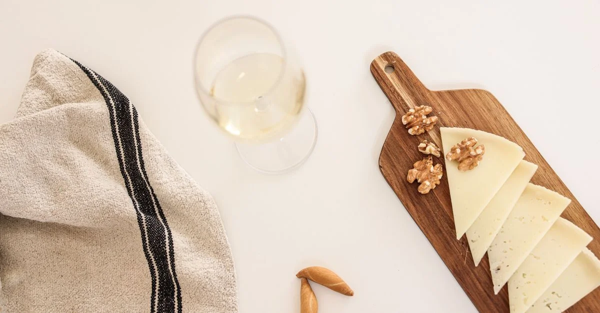 Élégant nature morte avec du fromage, des noix et du vin sur une planche en bois.